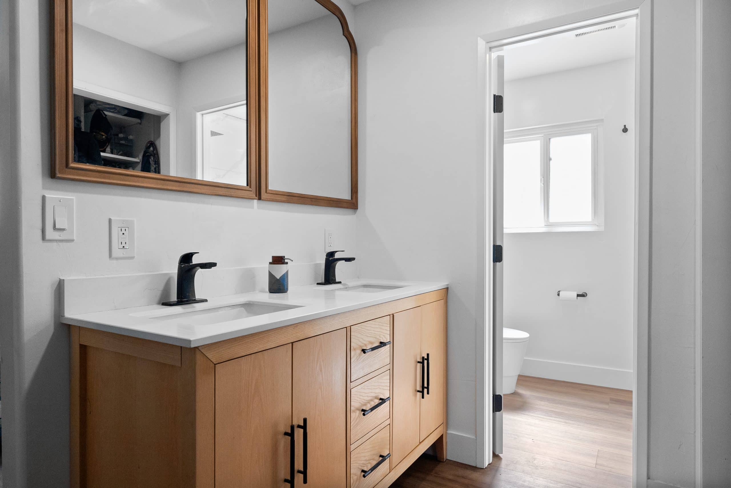 Vanity with wood-framed mirror and black faucet
