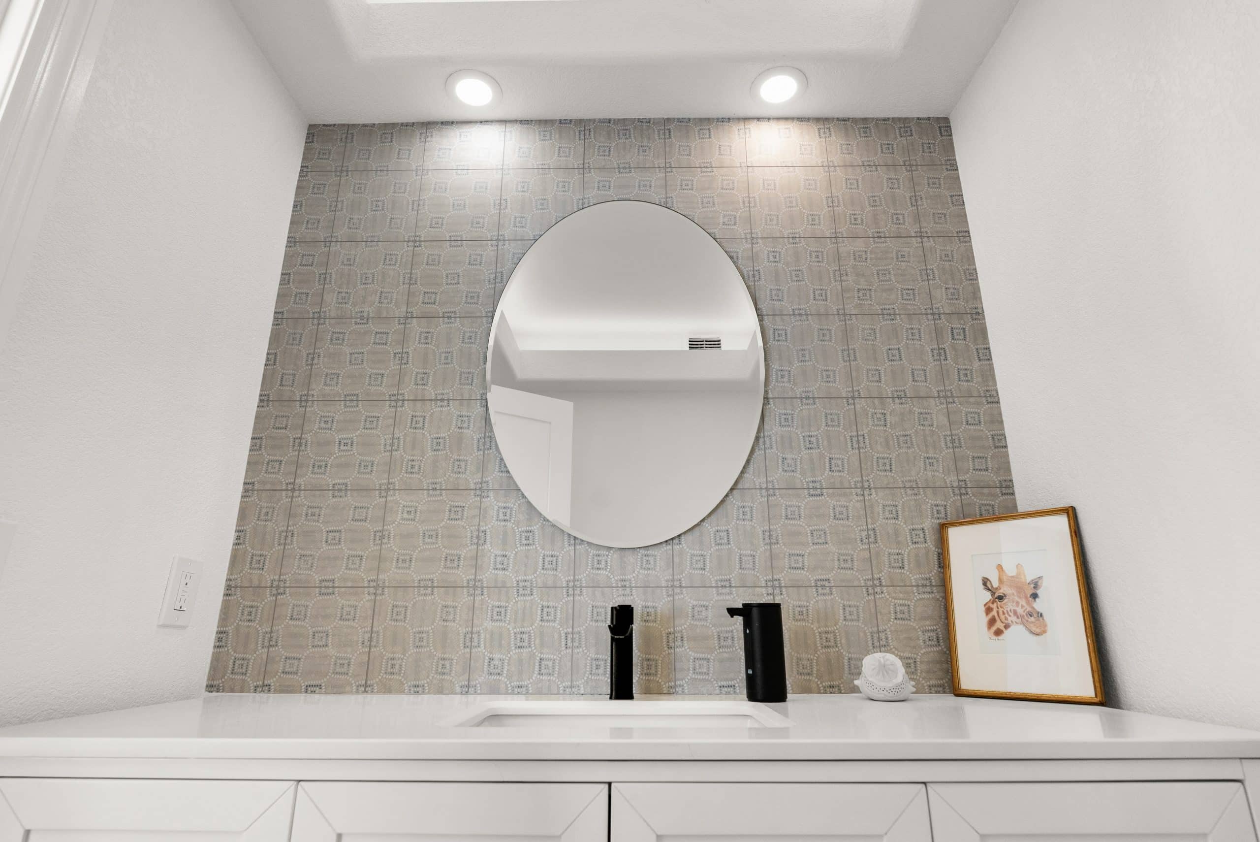 Powder bathroom with round mirror and decorative feature tile