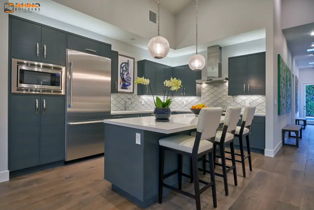 Contemporary kitchen with dark cabinets, stainless appliances, pendant lights, and a white island with upholstered barstools.