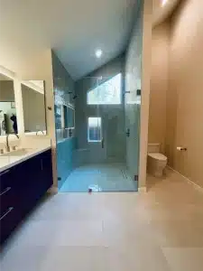 Modern bathroom remodel ideas featuring a double vanity with backlit mirrors and a glass walk-in shower with gray tile walls.