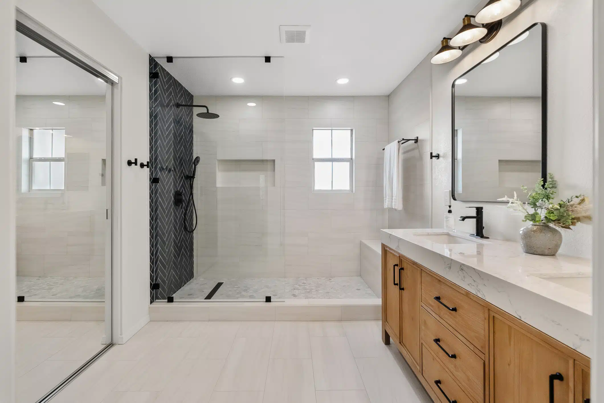 Moraga primary bathroom — walk-in shower with navy herringbone feature wall and wood vanity