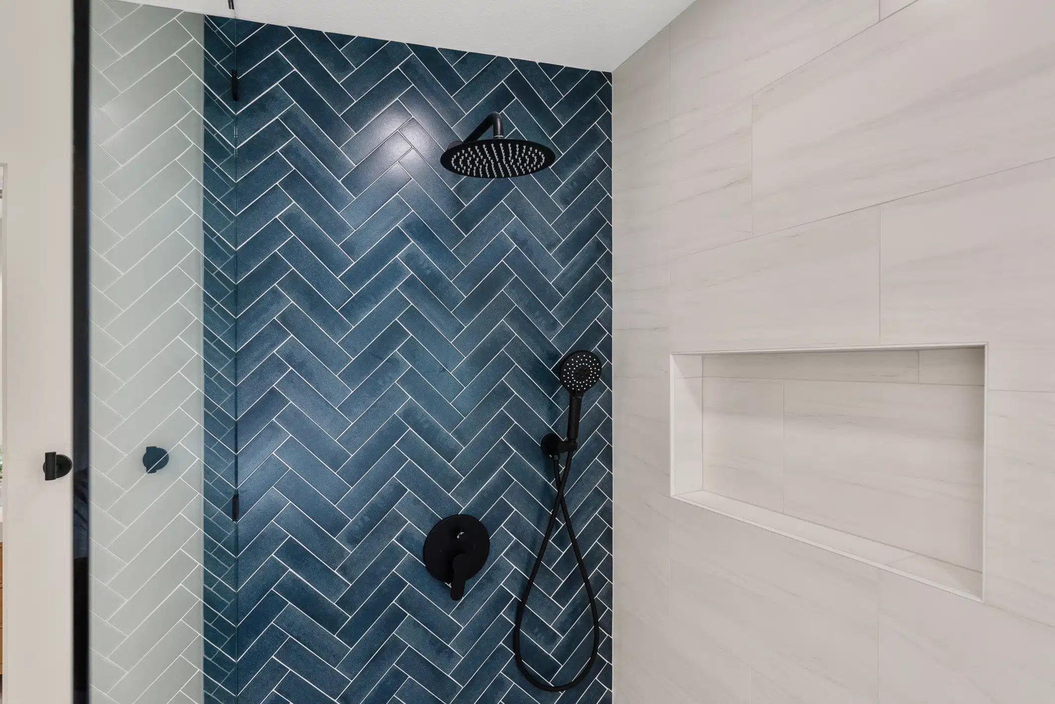 Moraga bathroom detail — navy herringbone shower tile and matte-black rainfall fixtures