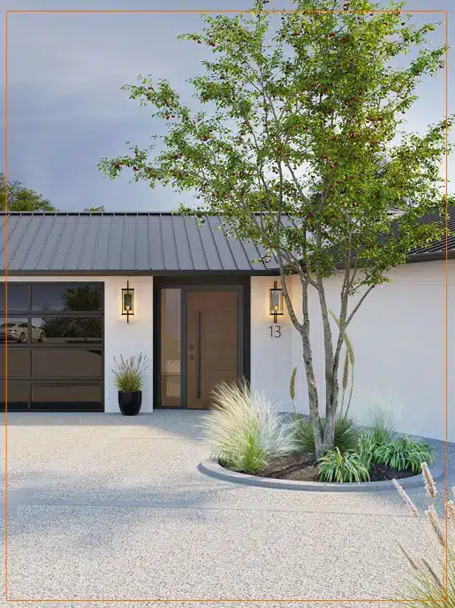 A modern minimalist home with white stucco walls and a dark metal roof features a covered entrance with large glass doors. A tall ornamental tree grows near the entryway, surrounded by decorative gravel and ornamental grasses, creating an understated landscape design. The architectural style emphasizes clean lines and contemporary aesthetics with natural elements integrated into the outdoor space.