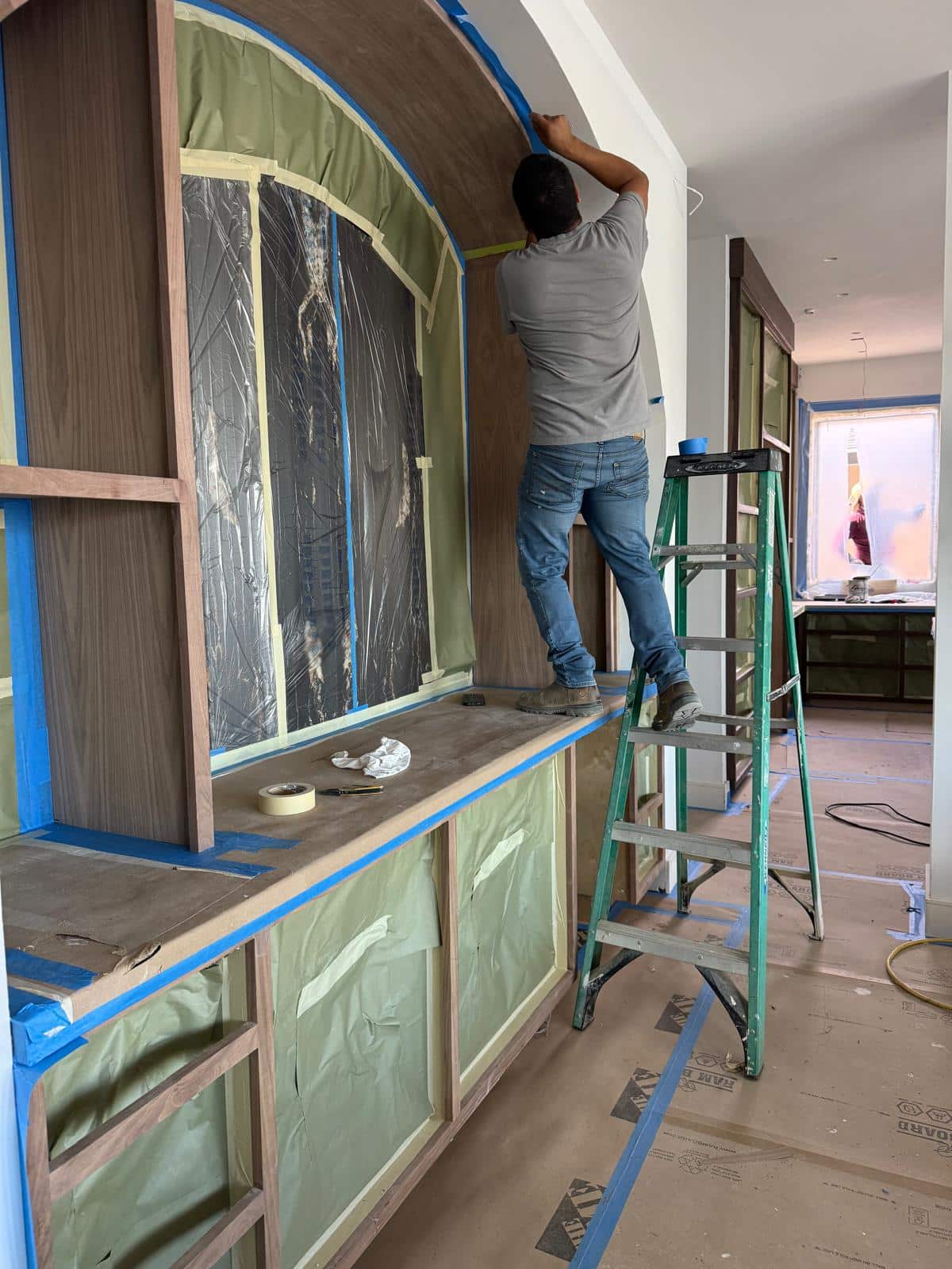 Custom arched cabinetry meticulously masked with tape and protective plastic by Rhino Builders in preparation for fine-finish painting during a Richmond CA kitchen remodel.
