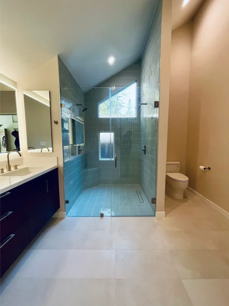 Modern bathroom remodel ideas featuring a double vanity with backlit mirrors and a glass walk-in shower with gray tile walls.