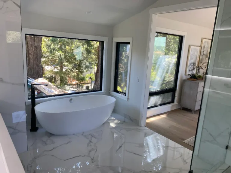 Contemporary bathroom featuring a freestanding tub, black fixtures, marble-look tile floors, and adjacent dressing area
