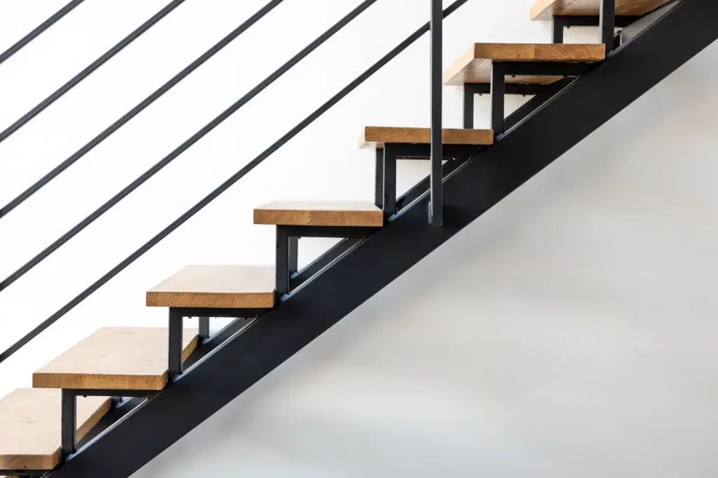 Modern staircase with wooden steps and black metal frame against a white wall.