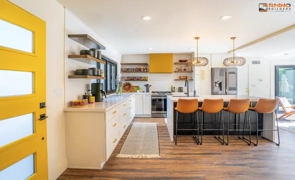 Bright kitchen with yellow accents, white cabinets, black island, open shelves, and modern pendant lighting.
